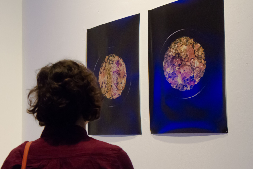 Eine Besucherin steht vor einer der Galeriewände und betrachtet ein Kunstwerk.